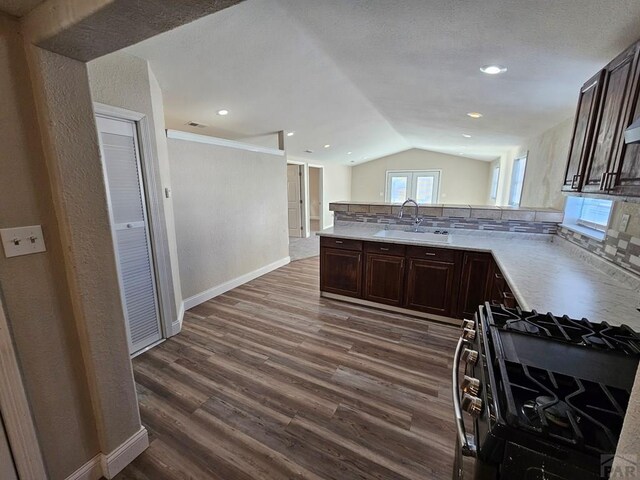 kitchen featuring stainless steel gas range oven, dark wood-style flooring, a sink, light countertops, and dark brown cabinets