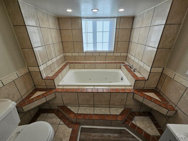 full bath featuring a whirlpool tub, toilet, tile walls, and recessed lighting