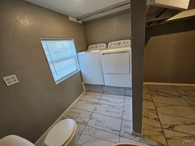 laundry area with a textured wall, laundry area, baseboards, marble finish floor, and independent washer and dryer