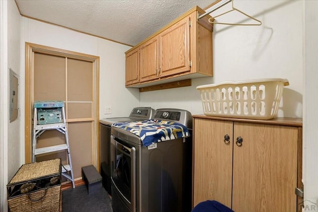 laundry area with a textured ceiling, washing machine and dryer, cabinet space, and electric panel