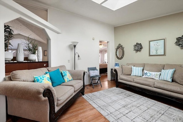 living room featuring a skylight, wood finished floors, and crown molding