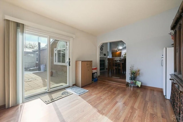 entryway featuring arched walkways, wood finished floors, and baseboards