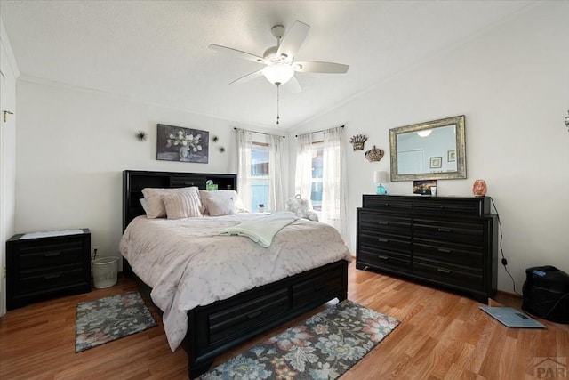 bedroom with light wood finished floors, vaulted ceiling, and a ceiling fan