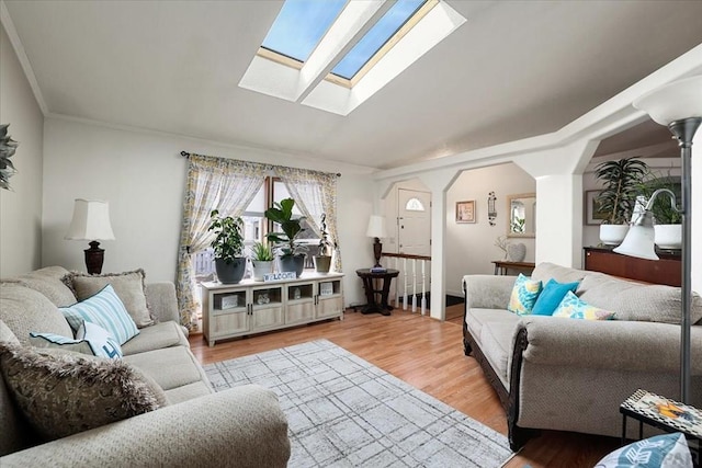 living area featuring light wood-style floors, a skylight, and arched walkways