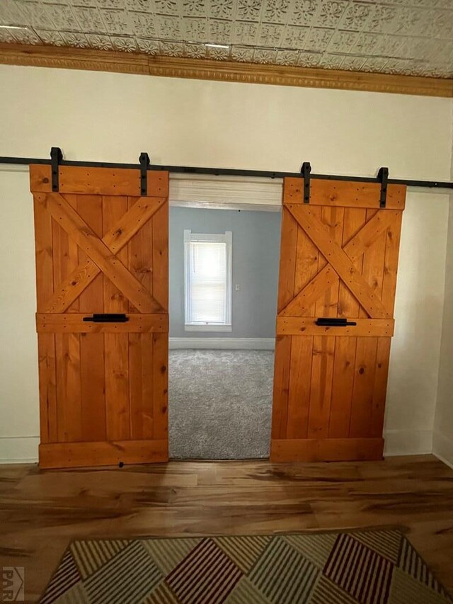 bonus room featuring an ornate ceiling, a barn door, baseboards, and wood finished floors