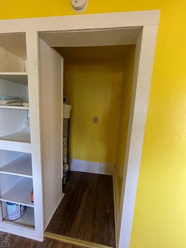 corridor with dark wood finished floors and baseboards