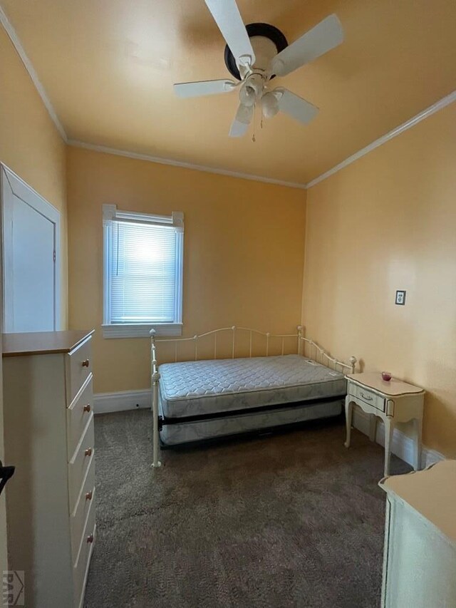 unfurnished bedroom with ceiling fan, ornamental molding, dark carpet, and baseboards