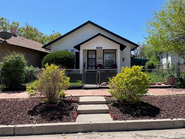 bungalow-style house featuring a fenced front yard, a gate, and stucco siding