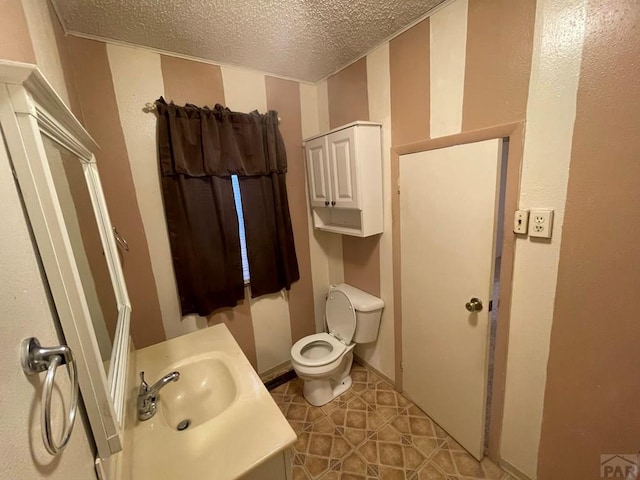 half bath featuring toilet, tile patterned flooring, a textured ceiling, and vanity