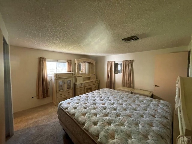 bedroom featuring carpet flooring, visible vents, and a textured ceiling