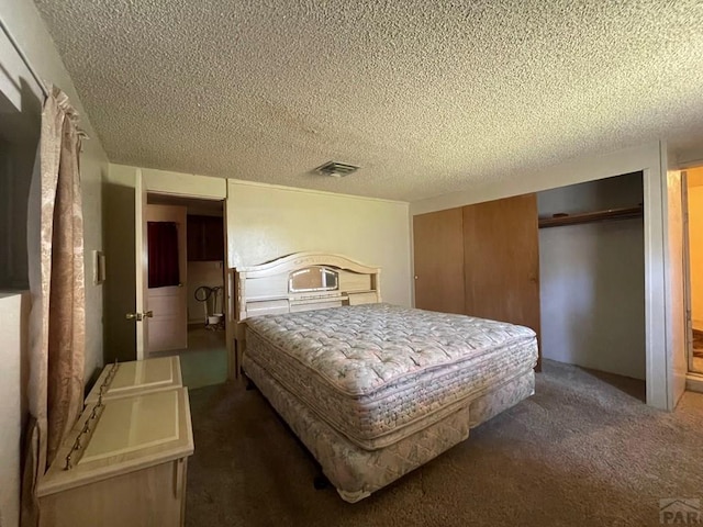 bedroom with dark colored carpet, visible vents, and a textured ceiling