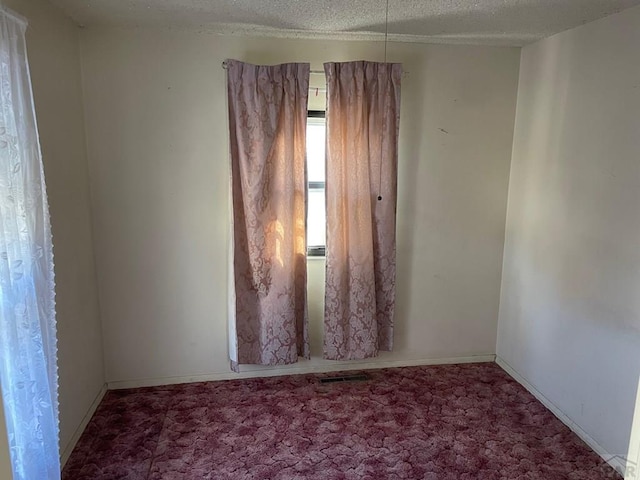 spare room featuring carpet flooring, a textured ceiling, and baseboards