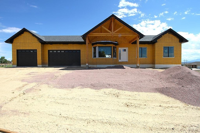 view of front facade featuring a garage, roof with shingles, and driveway