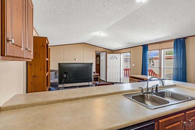 kitchen featuring a textured ceiling, a sink, lofted ceiling, brown cabinets, and light countertops