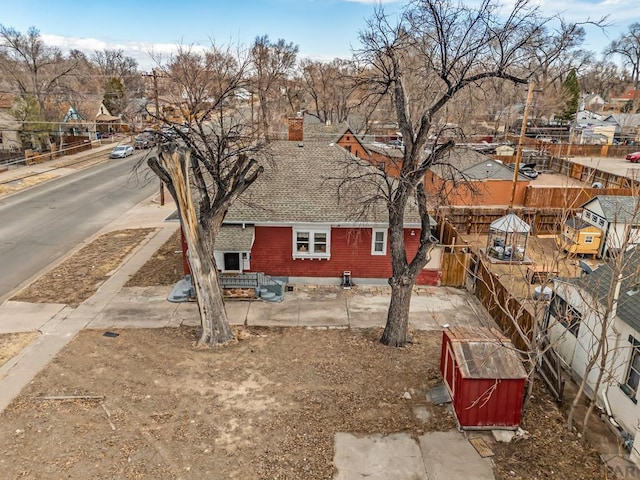 view of property exterior with brick siding, a chimney, a shingled roof, and a residential view