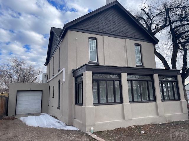 view of side of home featuring an attached garage and stucco siding