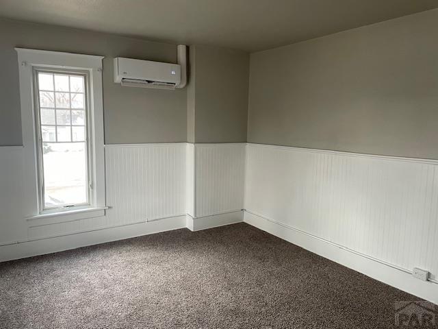 empty room with a wainscoted wall, a wall mounted AC, and plenty of natural light