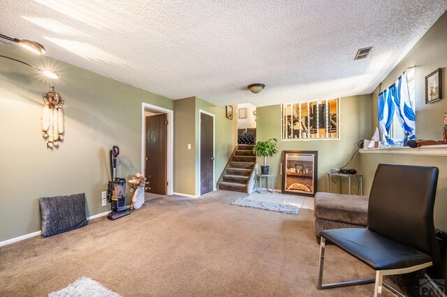 sitting room with baseboards, visible vents, stairway, a textured ceiling, and carpet floors