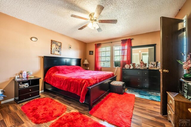 bedroom with ceiling fan, baseboards, dark wood finished floors, and a textured ceiling