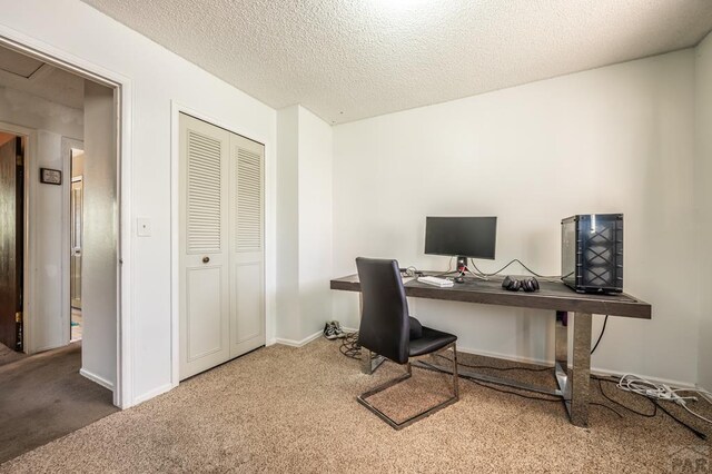 carpeted home office with a textured ceiling and baseboards