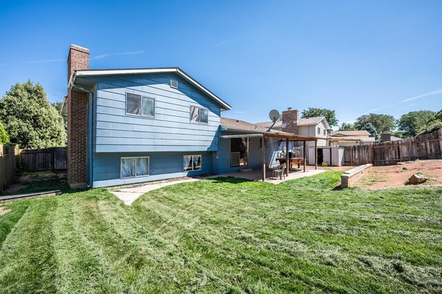 back of property with a patio area, a fenced backyard, a lawn, and a chimney