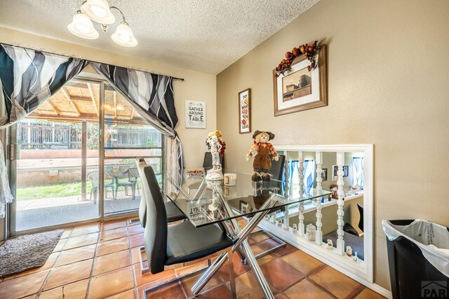 dining space with a notable chandelier, a textured ceiling, and tile patterned floors