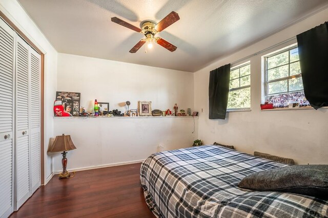 bedroom with dark wood-style floors, a closet, a ceiling fan, and baseboards