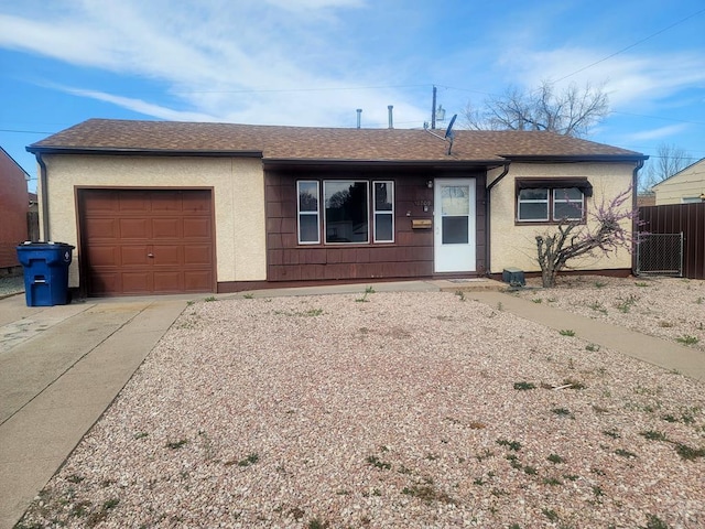 ranch-style home featuring roof with shingles, concrete driveway, fence, an attached garage, and stucco siding