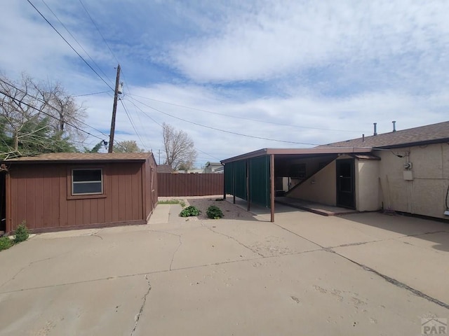 view of home's exterior with fence and an outbuilding
