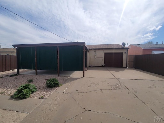 back of house featuring an attached garage, fence, driveway, and stucco siding