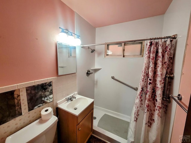 bathroom featuring tile walls, toilet, vanity, and a stall shower