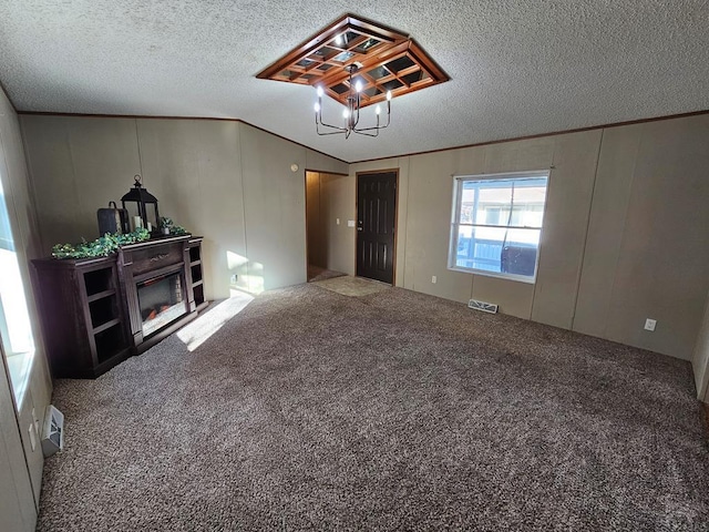 unfurnished living room featuring a textured ceiling, carpet floors, visible vents, ornamental molding, and a glass covered fireplace