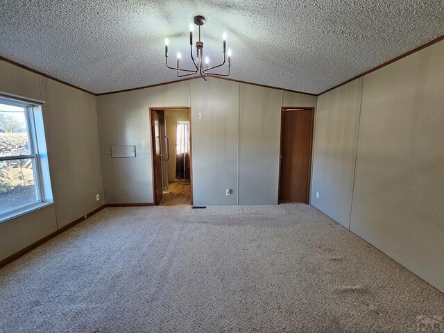 empty room with lofted ceiling, a textured ceiling, a chandelier, and crown molding