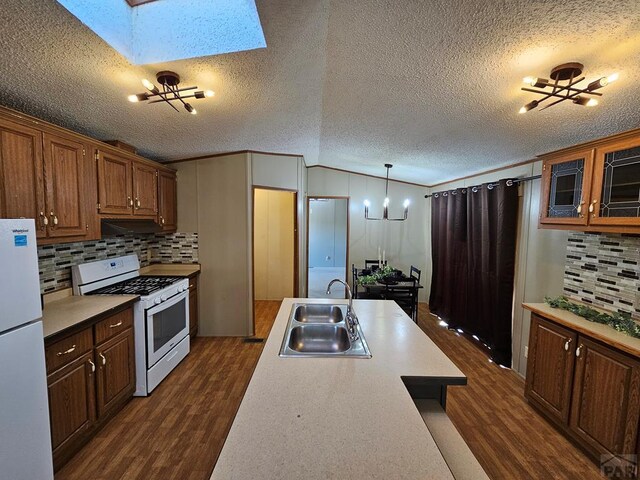 kitchen with white appliances, a notable chandelier, light countertops, and a sink