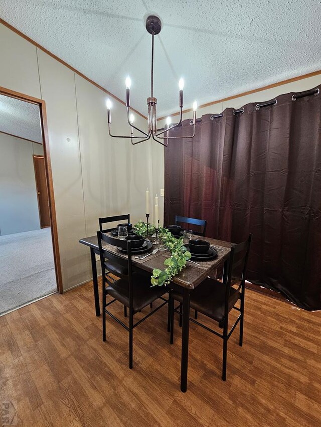 dining room with a textured ceiling, wood finished floors, lofted ceiling, and crown molding