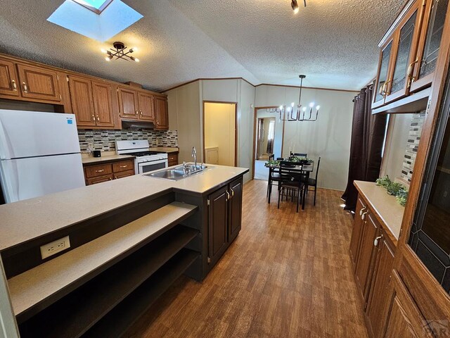 kitchen featuring light countertops, glass insert cabinets, brown cabinetry, a sink, and white appliances