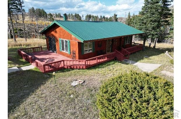 chalet / cabin with metal roof, a front lawn, and a wooden deck