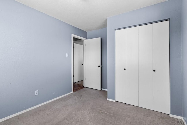 unfurnished bedroom with a closet, light carpet, and baseboards