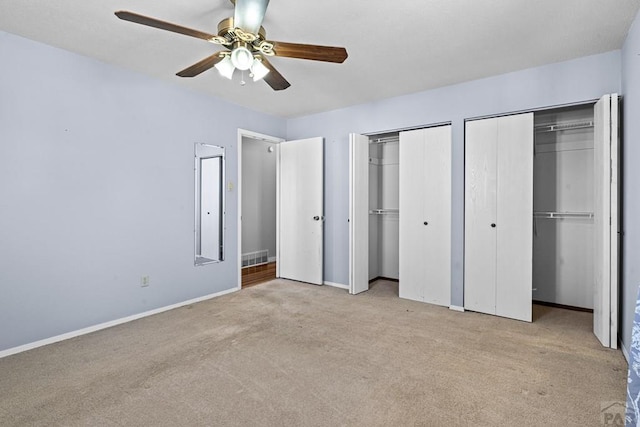 unfurnished bedroom featuring baseboards, a ceiling fan, light colored carpet, and multiple closets