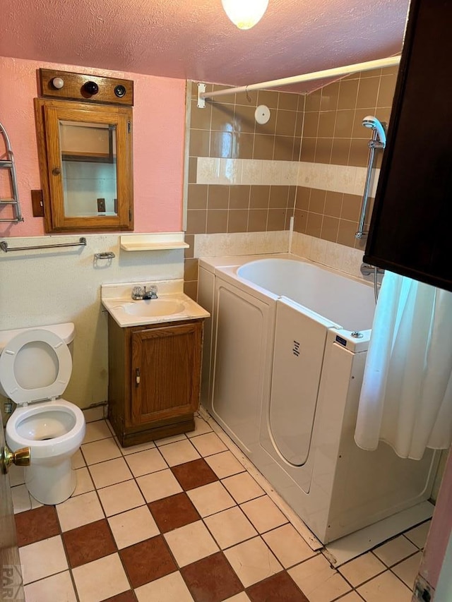 full bathroom featuring toilet, a textured ceiling, bathtub / shower combination, and vanity