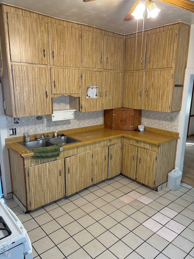 kitchen featuring white range oven, brown cabinets, a sink, and decorative backsplash