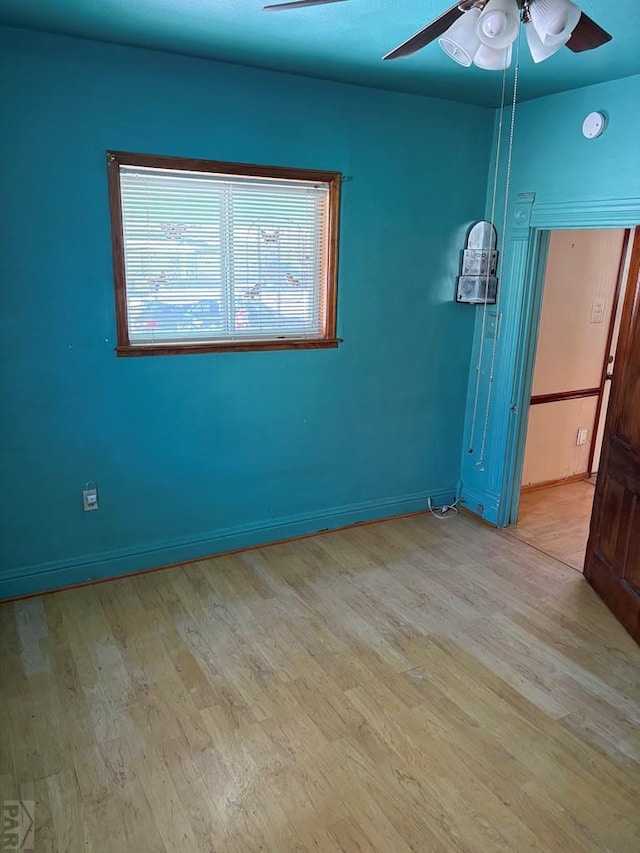 empty room featuring a ceiling fan, baseboards, and light wood finished floors