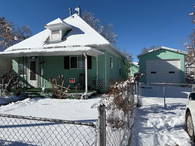 view of front of house featuring a porch, fence, and a detached garage