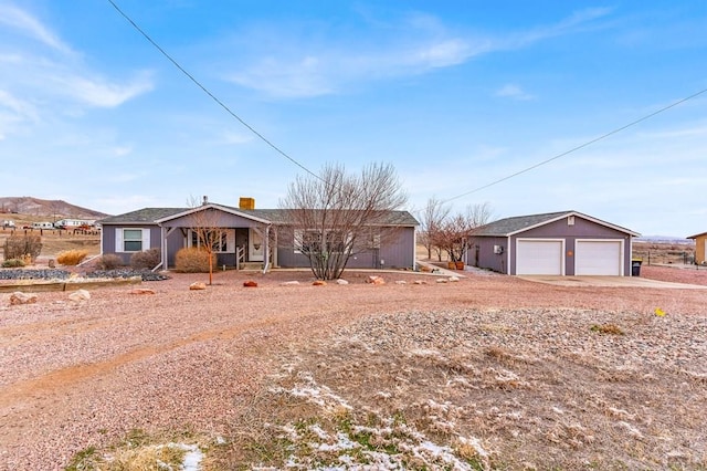 ranch-style home with an outdoor structure, a chimney, and a detached garage