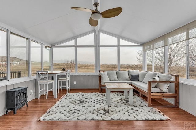 sunroom featuring a wood stove, a deck, and wood finished floors