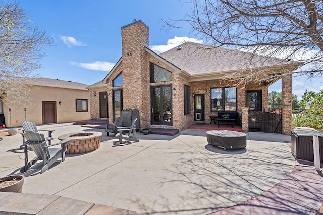 back of house featuring a chimney, an outdoor fire pit, a patio, and brick siding