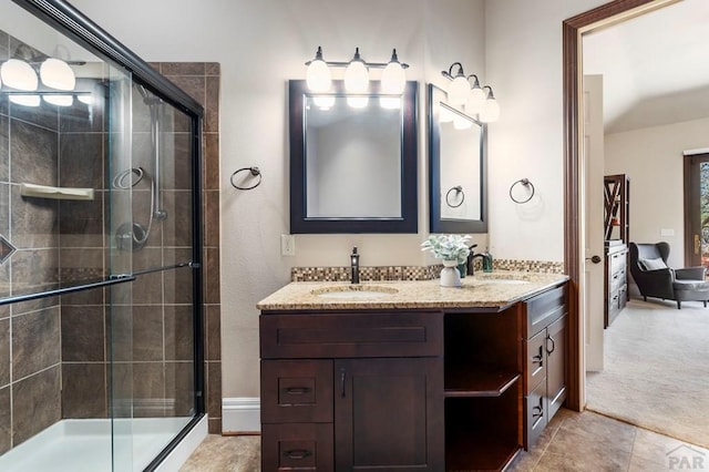 bathroom with a stall shower, double vanity, and a sink
