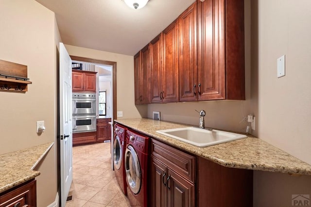 washroom with light tile patterned floors, independent washer and dryer, cabinet space, and a sink