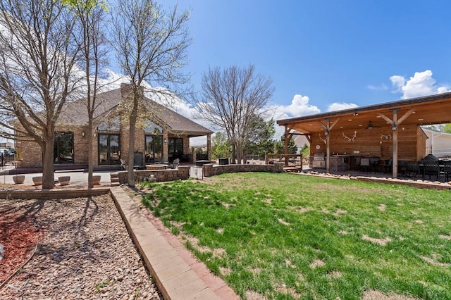 view of yard with ceiling fan, a patio, and an outdoor kitchen