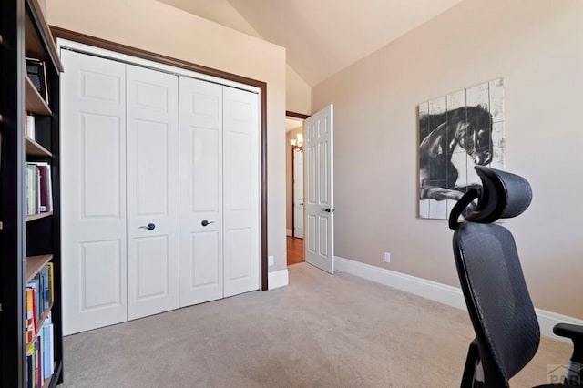 carpeted office space featuring baseboards and vaulted ceiling